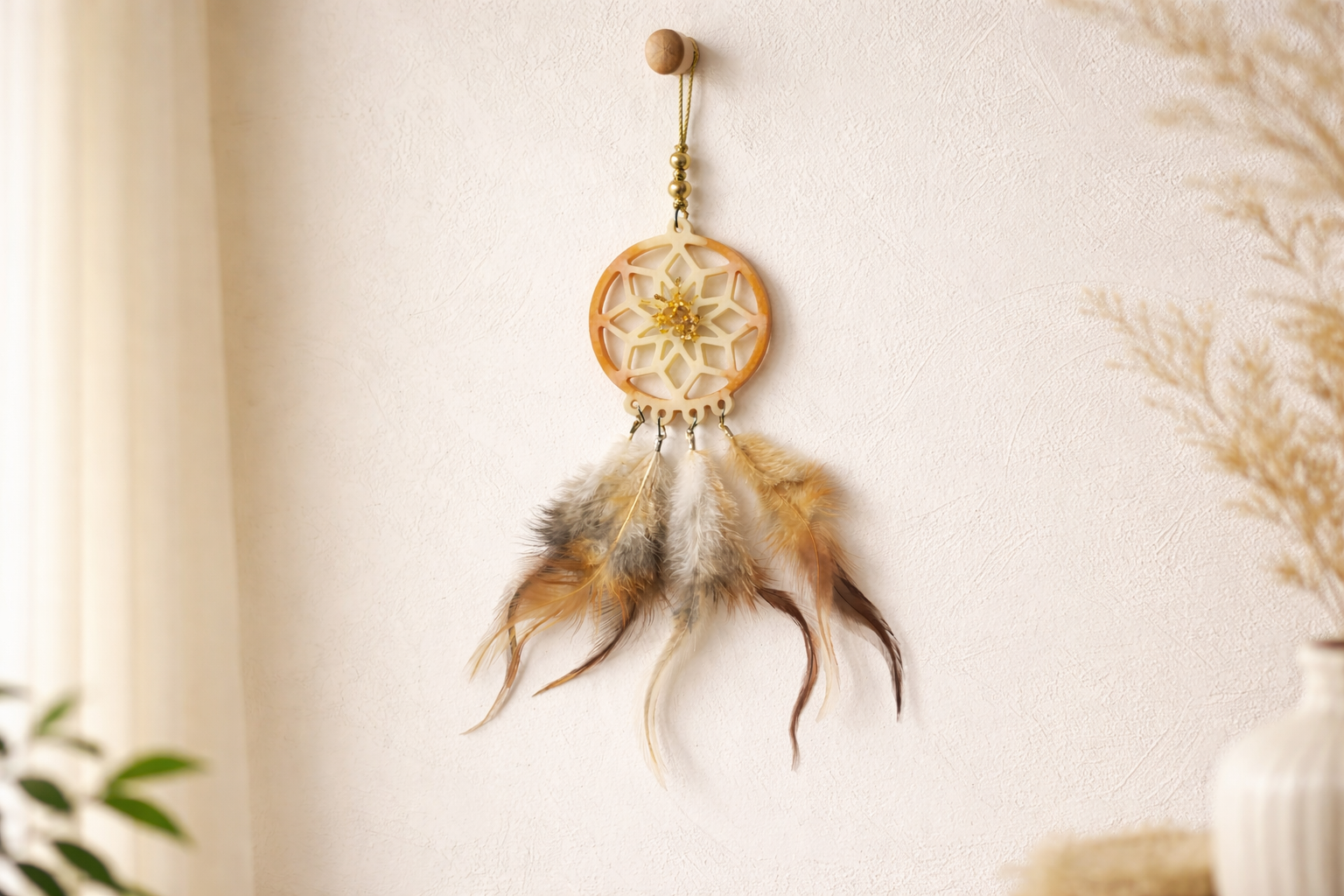 Dreamcatcher with feathers hanging on a white wall