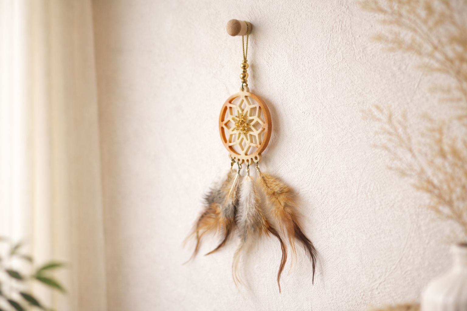 Dreamcatcher with feathers hanging on a white wall
