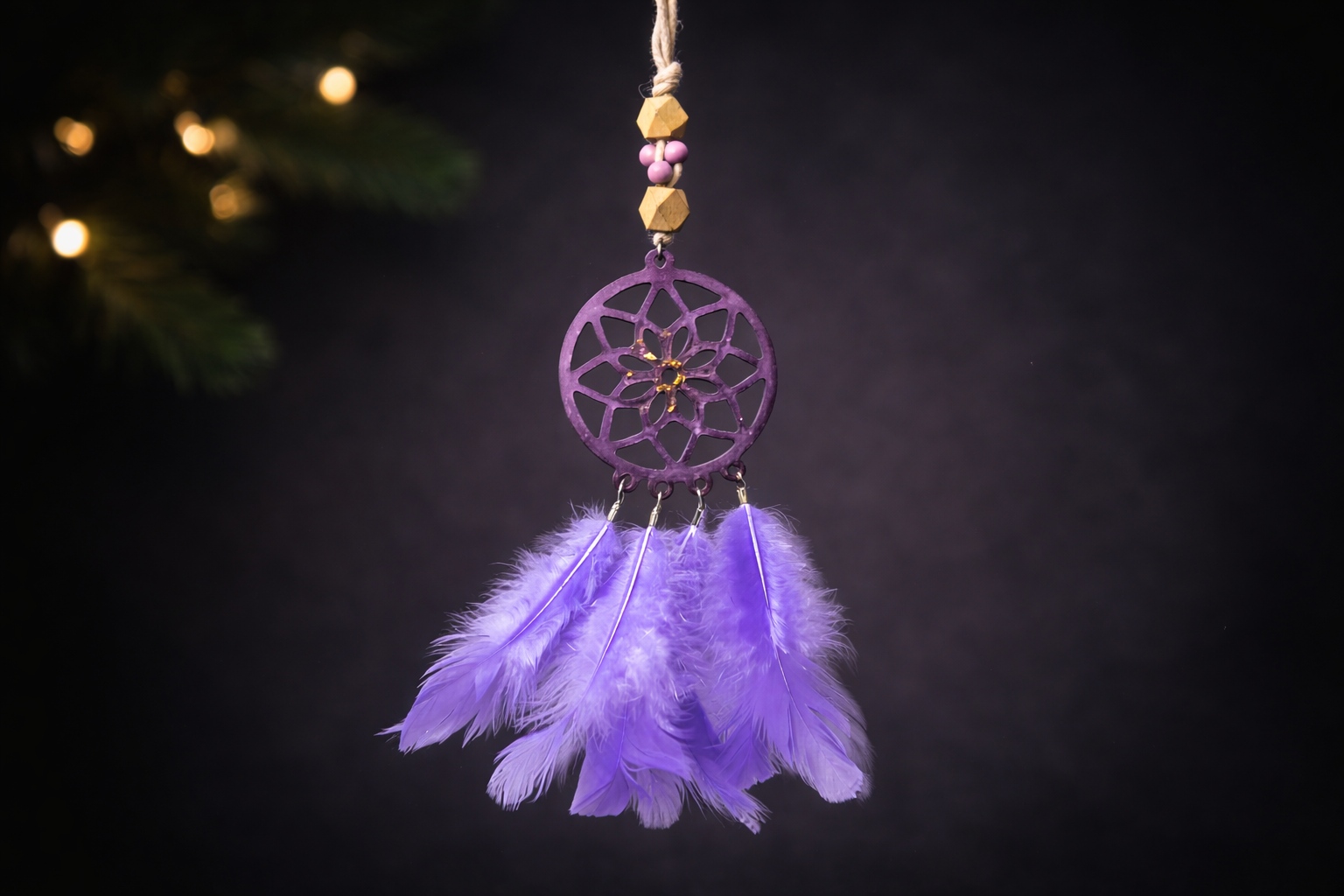 Purple dreamcatcher with feathers hanging against a dark background